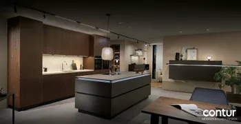 Moderne Designküche von Contur mit dunklen Holzfronten, beleuchteter Kochinsel in Metalloptik und integrierten Geräten; stimmungsvolle Beleuchtung, minimalistische Einrichtung und elegantes Ambiente.